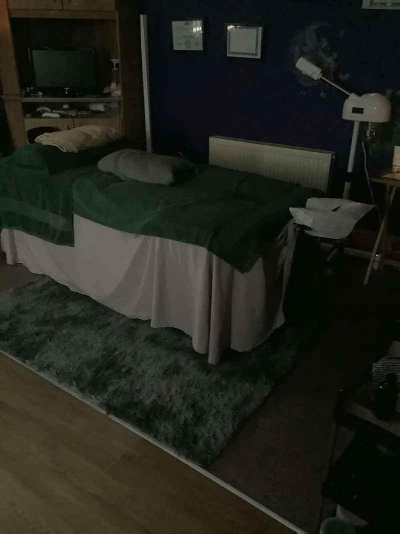 Massage table set up with a green throw in a treatment room